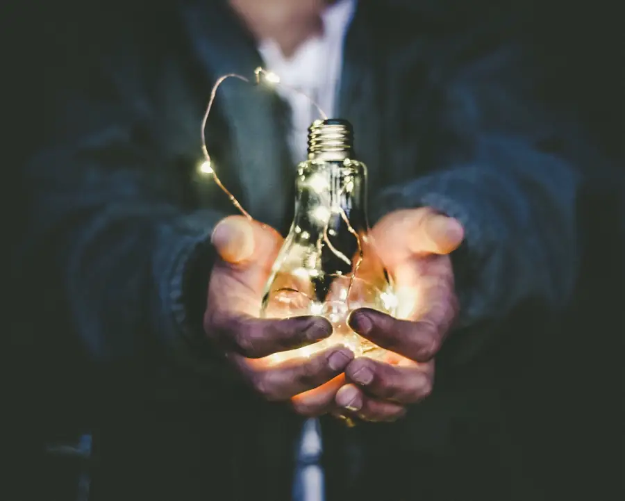 Hands holding a glowing light bulb